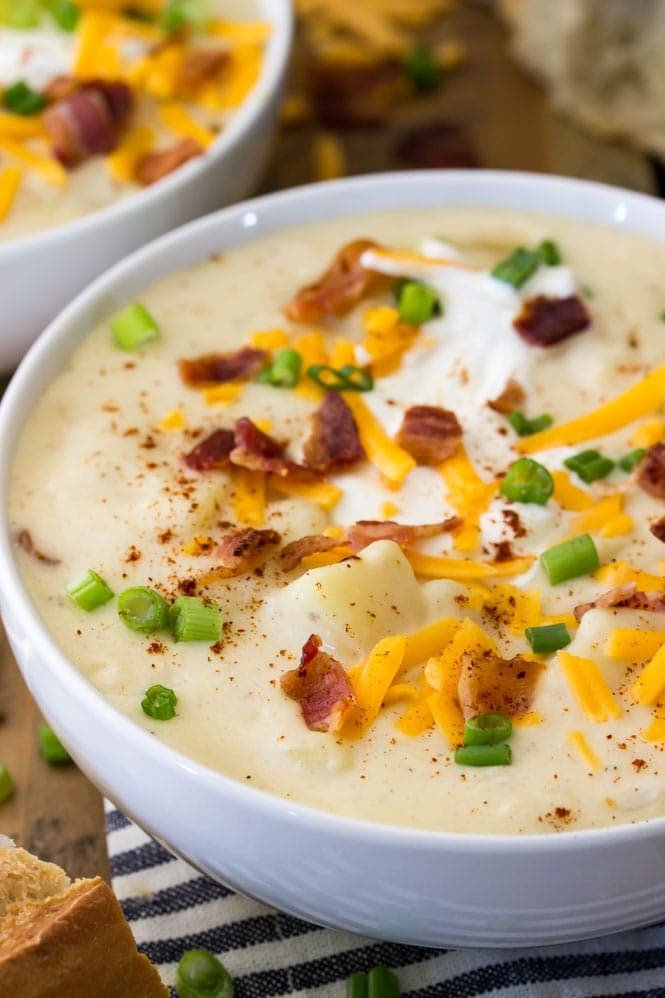 How to make the best potato soup A close up view of creamy potato soup, topped with bacon, sour cream, chives, and cheddar cheese