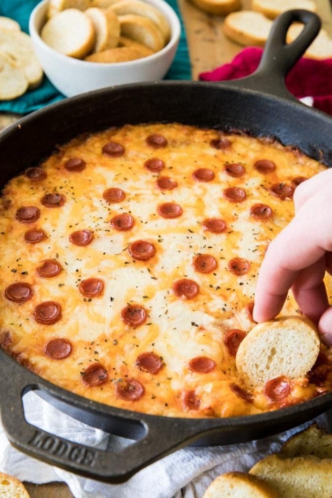 Slice of bread dipped in skillet of pizza dip