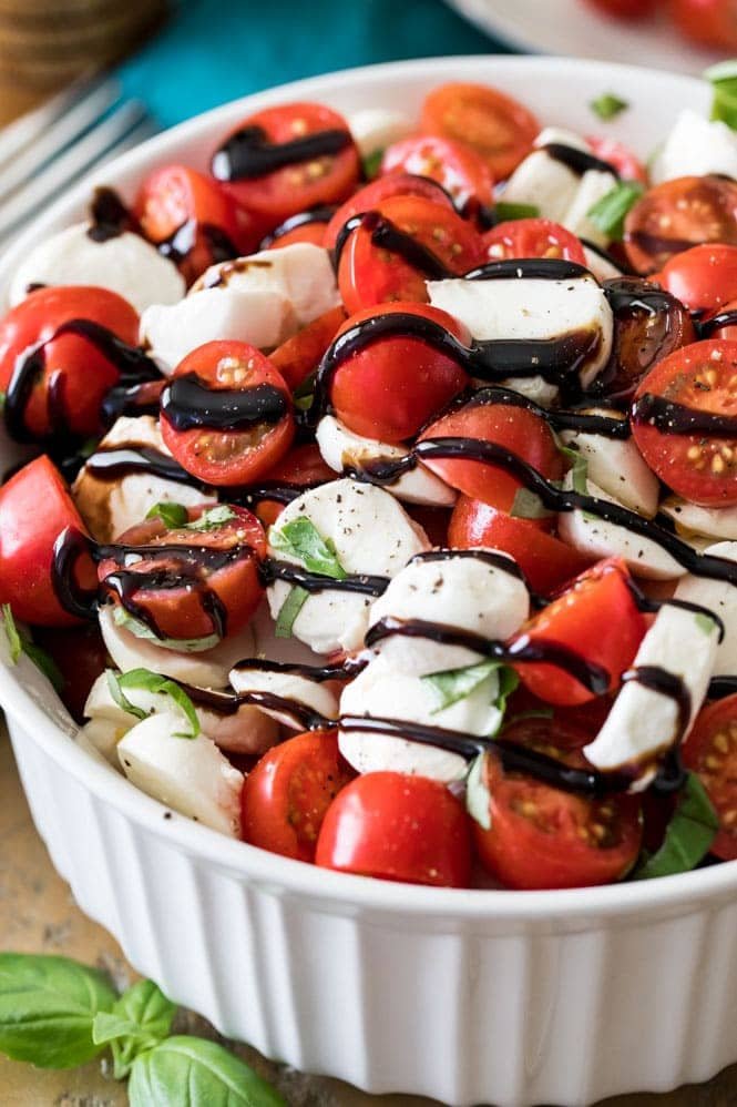 Caprese Salad is a classic and refreshing summertime salad! This is a great recipe for any potluck, picnic, or party! Easy and delicious salad! #saladrecipe #caprese #tomatorecipe #summerfood #sugarspunrun Caprese salad drizzled with balsamic reduction
