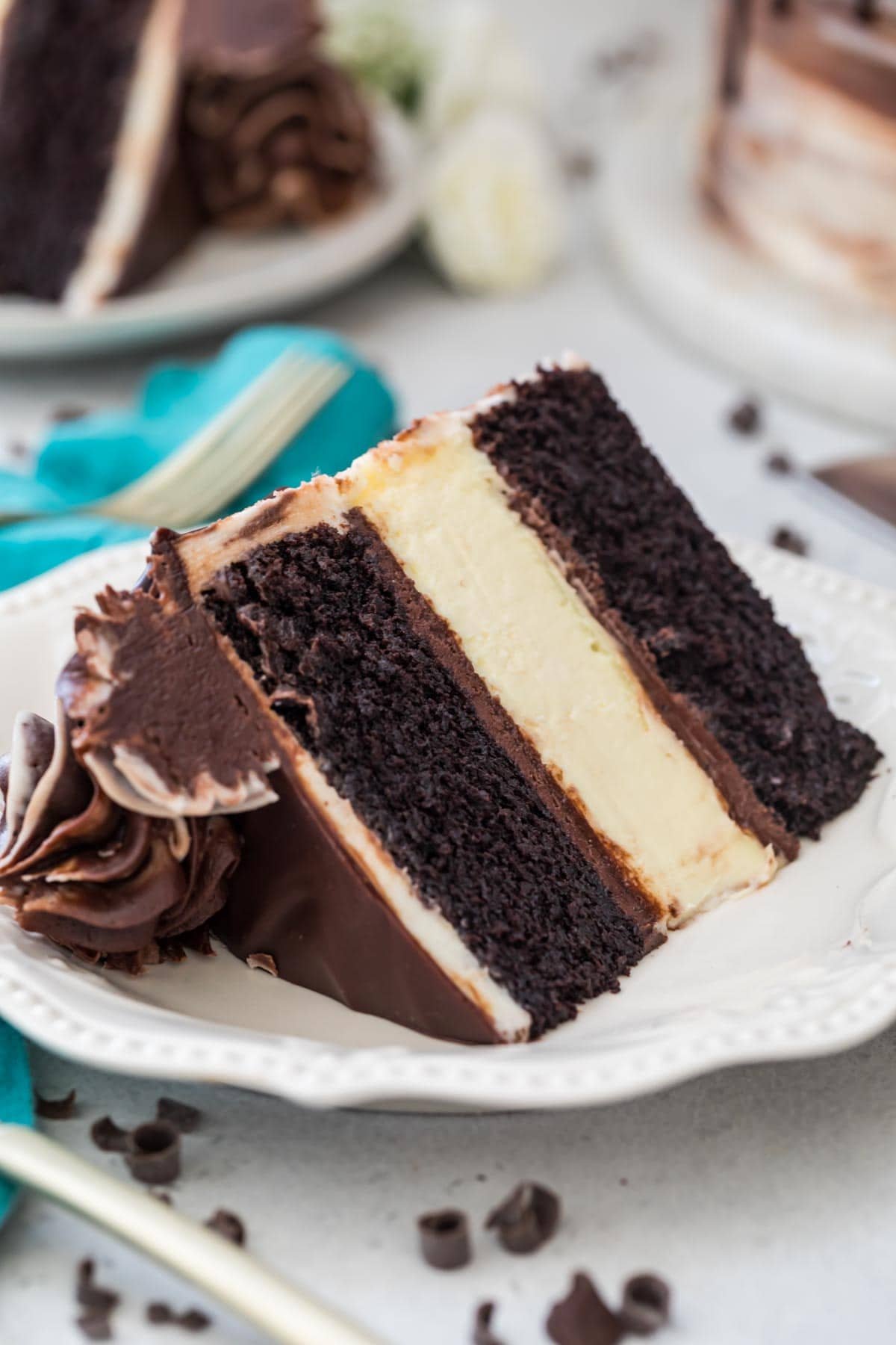 slice of cheesecake stuffed cake with clear, defined layers of dark chocolate cake and classic cheesecake on a white plate