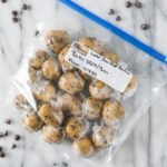 Ziploc bag of cookie dough balls that have been wrapped in plastic in preparation for freezing.