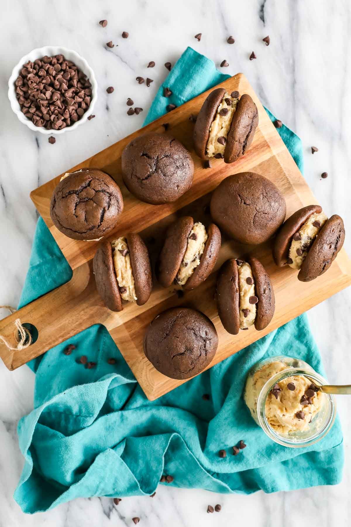 Overhead view of cookie dough whoopie pies on a wood cutting board.