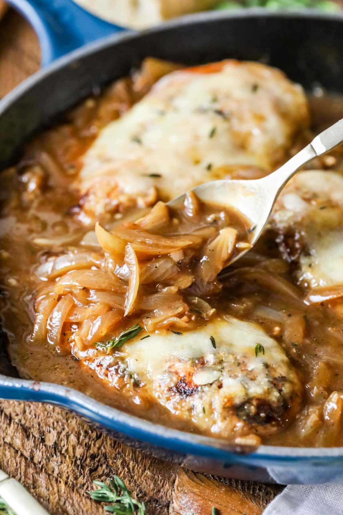 Caramelized onion gravy being spooned over french onion chicken.