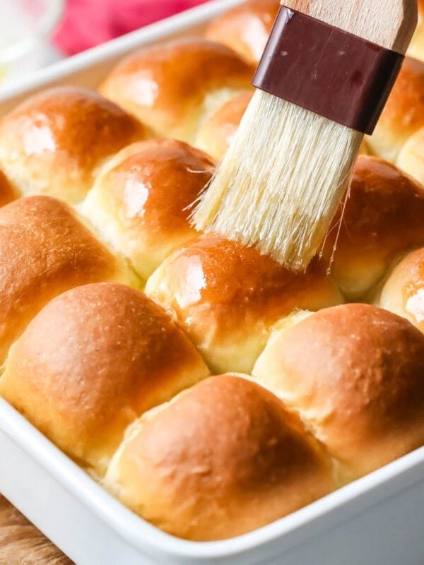 Melted butter being brushed onto make ahead dinner rolls.