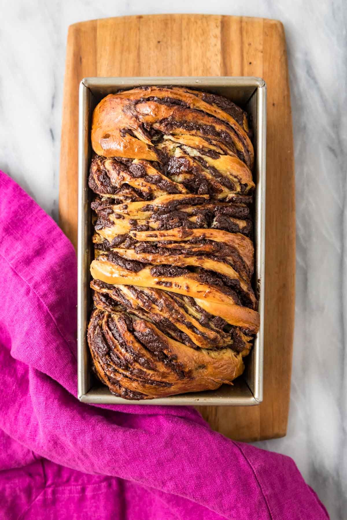 Overhead view of a loaf of chocolate babka in a pan.