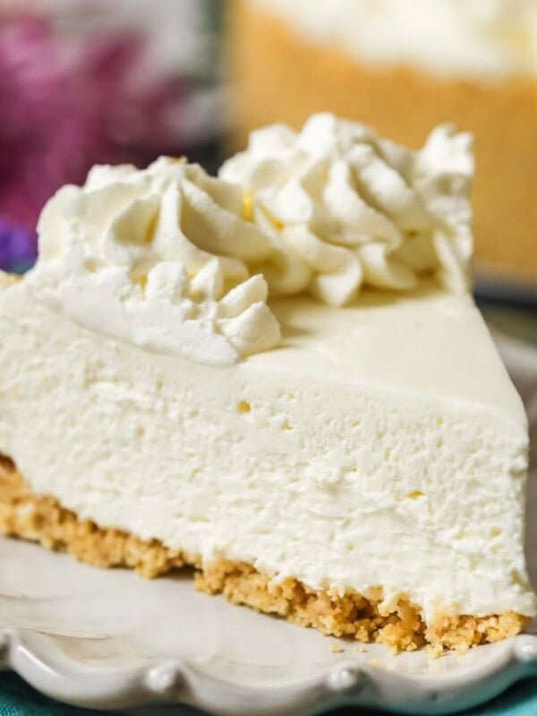 Slice of no-bake cheesecake with a whipped cream topping on a plate.
