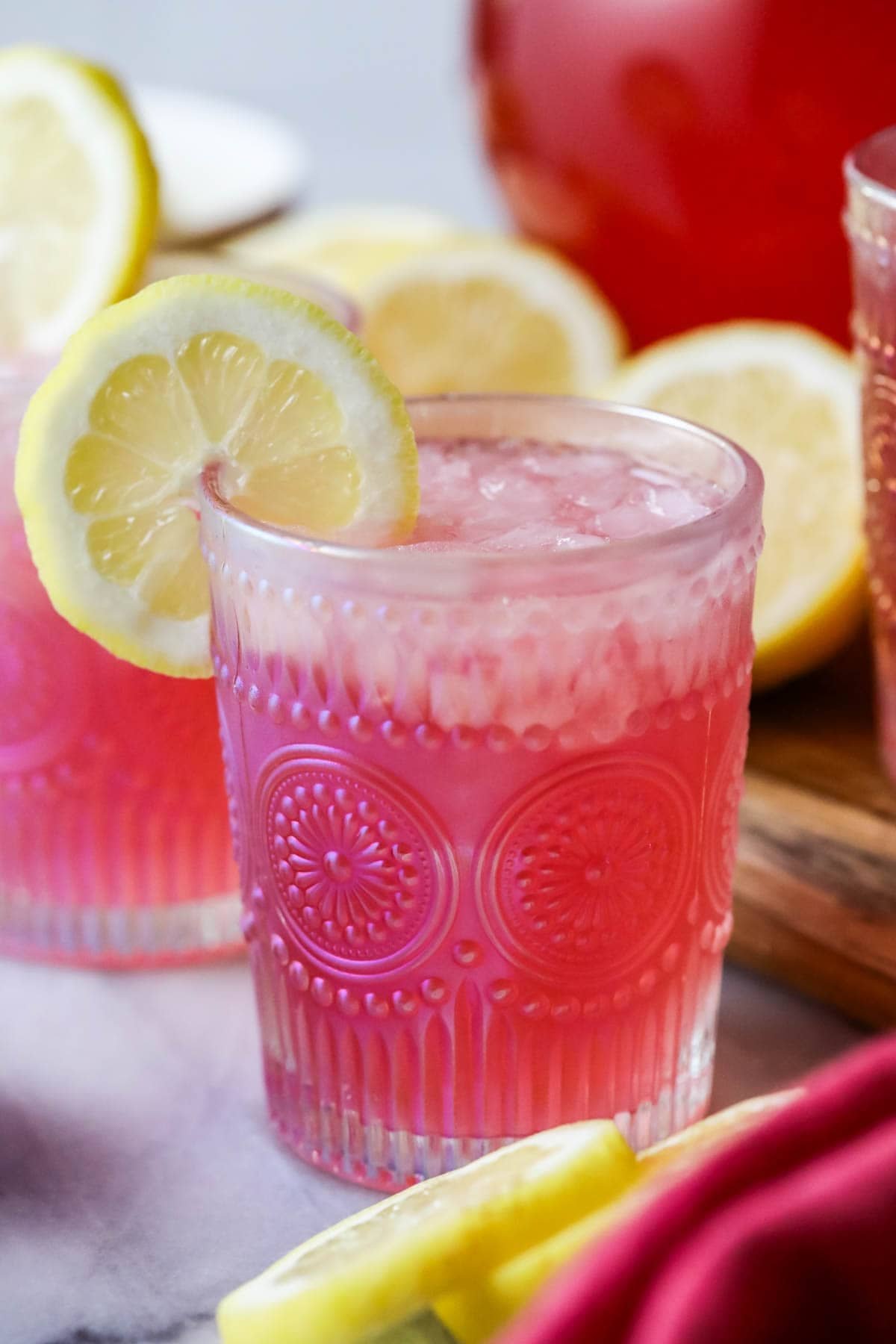 Glass of pink lemonade garnished with a lemon slice.