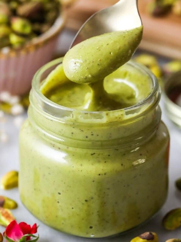 Spoon dipping into a small jar of homemade pistachio cream.