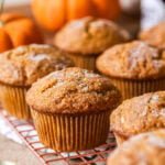 Sourdough pumpkin muffins topped with coarse sugar on a cooling rack.